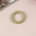 Matte light green spiral phone cord hair tie on a minimalist lifestyle background - Matte Matcha Green