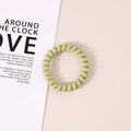 Elastic light green spiral telephone wire hair tie on a decorative soft pink background - Glossy Matcha Green