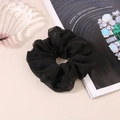 Detail shot of a black oversized scrunchie in light chiffon fabric on a desk - Smooth Chiffon (C4176) / Black