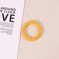 Elastic yellow telephone wire hair coil in spiral design on a soft beige background - Glossy Orange