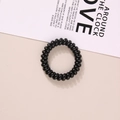 Elastic black spiral hair tie with a shiny finish on a minimalist fashion background - Glossy Black