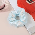 Détail d'un chouchou bleu clair à fleurs avec tissu en organza et texture plissée - Floral Bleu