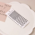 20-piece set of matte black wavy bobby pins arranged on a display card in a ceramic dish - Style G