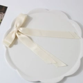 Elegant off-white satin bow hair clip with long ribbons on a ceramic plate - Milk White