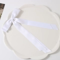 White satin ribbon bow hair clip with elegant long streamers on a white ceramic plate - White