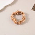 Gros plan sur l'élastique à cheveux en perles champagne sur fond minimaliste - Perle-Or