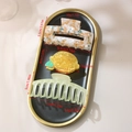 Three candy-colored acetate hair claws including floral and lemon styles in a tray - Style E