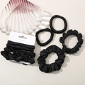 Detail of elegant black satin scrunchies and elastic hair ties on a shell tray - Black