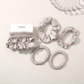 Detailed view of champagne silk scrunchies set with satin texture and elegant beads - Warm Gray