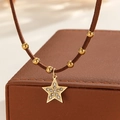 Dettaglio macro del ciondolo a stella dorata con cristalli su collana in pelle - Stile Stella Strass (S-N2298-B)