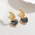 Orecchini vintage a cuore dorati con pietre blu glitterate su sfondo bianco materico - Pietra Blu Scuro