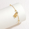 Detail eines Goldbienenarmbandes mit Kristallakzenten und kleinen Perlen auf Weiß - Bienenanhänger / Gold