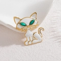 Détail de la broche chat en émail blanc avec yeux en gemme verte et contour en métal doré - Chat