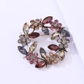 Detailed macro view of vintage gold wreath brooch with inlaid multicolor crystals and rhinestones - Vintage Gold Grey And Purple