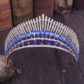 Macro shot of gold peacock crown with blue crystals on a vintage book backdrop - KC Gold With Blue Crystals