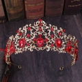 Vintage golden bridal crown with red rhinestones and intricate leaf patterns on a dark wood base - KC Gold Red Rhinestone
