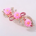 Nahaufnahme einer eleganten Gold-Haarklammer mit rosa Harzblüten und Glitzersteinen - Roségold Doppellagig Rosa