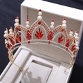 Détails macro d'une couronne dorée avec cristaux rouges et perles blanches en boîte - Or avec strass rouges