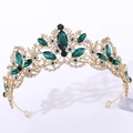Dettaglio della corona dorata con pietre verde smeraldo e strass trasparenti lucidi - Oro con strass verdi