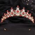 Dettaglio di corona dorata vintage con strass rossi su sfondo di tessuto nero - KC Oro Strass Chiaro e Rosso