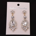 Close-up of oversized drop earrings with sparkling crystals on Fashion Jewelry card - Gold White Earring Post Earrings