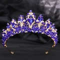 Dettaglio della corona barocca dorata con cristalli blu profondo e intricati motivi a foglie - Oro con pietra blu