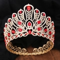 Vue détaillée d'une grande couronne dorée sertie de cristaux rouges et de strass étincelants - Or KC Diamant Blanc + Grand Diamant Rouge