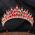 Dettaglio di corona nuziale dorata con strass rossi su fondo in legno vintage - Oro Strass Bianco + Rosso