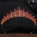 Detailed close-up of a vintage golden tiara with ruby red rhinestones on dark wood - KC Gold White Diamond + Large Red Diamond