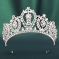 Nahaufnahme einer silbernen Barock-Tiara mit glänzenden Strasssteinen auf grünem Stoff - Dickes Silber Weißer Strass