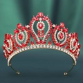 Detailed close-up of Baroque gold crown with red gemstones on dark green silk - KC Gold White Diamond + Large Red Diamond