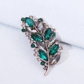 Luxury rose gold leaf brooch with emerald and smoke gray crystals on blue background - Antique Copper Green Rhinestone