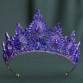 Detail of baroque gold crown with deep blue crystals on dark green velvet background - KC Gold Royal Blue Crystal