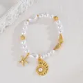 Detailed shot of pearl bracelet featuring golden starfish and shell charms on white background - Pearl Conch