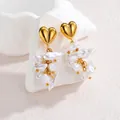 Détail de clous dorés en forme de cœur avec perles baroques suspendues sur support pierre - Doré