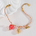 Detail eines geflochtenen Armbands mit Erdbeer-, Herz- und Walanhängern aus Edelstahl - Erdbeere + Herz