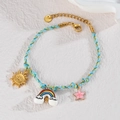 Detail of woven rope bracelet with colorful enamel sun rainbow and star charms - Sun + Rainbow