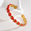 Detalle de los motivos de fresa esmaltados en un brazalete dorado pulido abierto - Brazalete con Forma de Fresa / Fresa