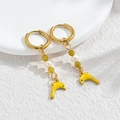 Detail of gold hoop earrings with green beads and yellow dolphin dangle on white surface - Yellow Dolphin / Gold