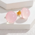 Dettaglio di orecchini a bottone rosa traslucidi con glitter e perni in metallo dorato - Rosa