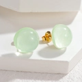Macro shot of light green resin stud earrings with glitter finish and S925 gold-plated backs - Green