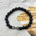 Natural lava rock beaded bracelet featuring a silver dumbbell charm on a textured background - Gun Black Lava Stone