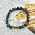 Blue volcanic stone beaded bracelet with golden dumbbell charm on white rock background - Blue Weathered Gold
