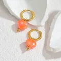 Detail van de schelpoorbellen in 18K goud en een heldere oranje afwerking - Oranjerood