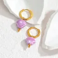 Detail van S925 zilvermerk op gouden schelpoorringen met een parelmoerachtige glans - Paars