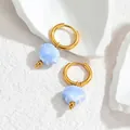 Detailopname van gouden schelpoorringen met lichtblauwe hangers op een stenen basis - Lichtblauw