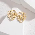 Macro shot of gold hollow monstera leaf earrings on a minimalist white stone pedestal - Leaf Stud Style / Gold