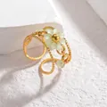 Détail macro d'une bague fleur dorée avec perles en cristal vert clair et anneau perlé - vert clair
