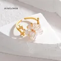 Détail de la bague ouverte dorée avec perles en cristal en forme de fleur sur pierre - Blanc