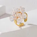 Detailaufnahme eines goldenen verstellbaren Rings mit einer Blume aus facettierten Perlen - Weiß